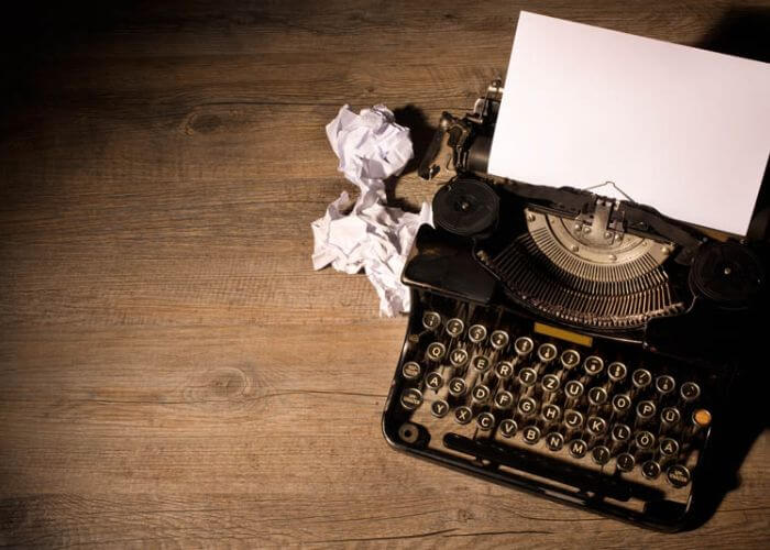 Typewriter with crumpled sheets next to it
